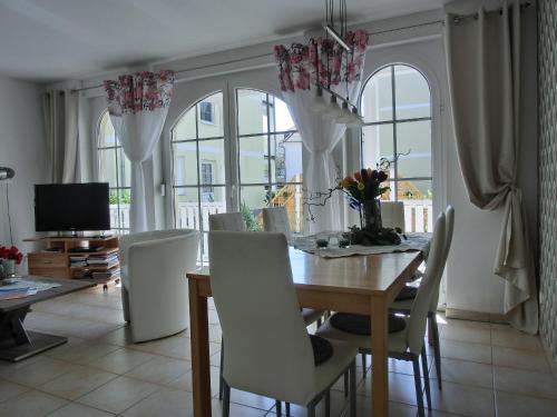 a dining room with a table and chairs and windows at Ferienwohnung KK26 in Graal-Müritz