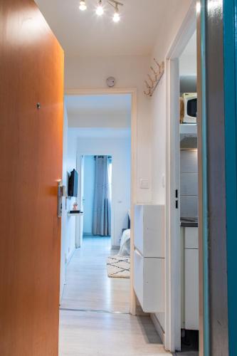 un couloir menant à une cuisine avec des armoires blanches dans l'établissement Le Victorieux - Appart 2 pièces -Proche Paris, à Clichy
