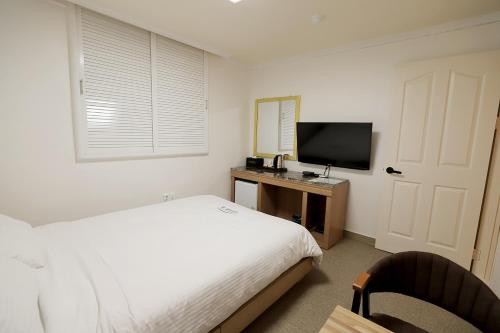 a bedroom with a bed and a desk with a television at Stay RomanticTrip_Hostel in Gyeongju