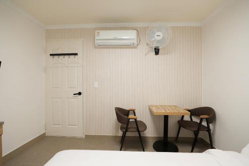 Stay RomanticTrip_Hostel في جيونجو: غرفة نوم مع طاولة وكراسي ومروحة