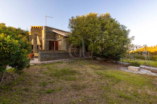 an image of an old stone house with trees at Il Glicine Cala Lupo in Stintino