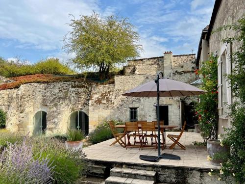 a patio with a table and an umbrella at Villa de charme tourangelle in Vallères