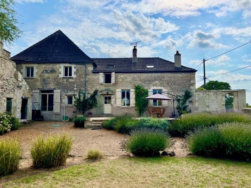 une vieille maison en pierre avec un jardin devant dans l'établissement Villa de charme tourangelle, à Vallères