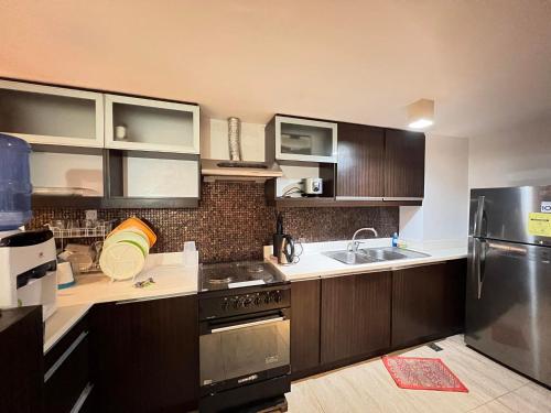 a kitchen with wooden cabinets and a stainless steel refrigerator at Home-like 2BR Unit in the Center in Cebu City