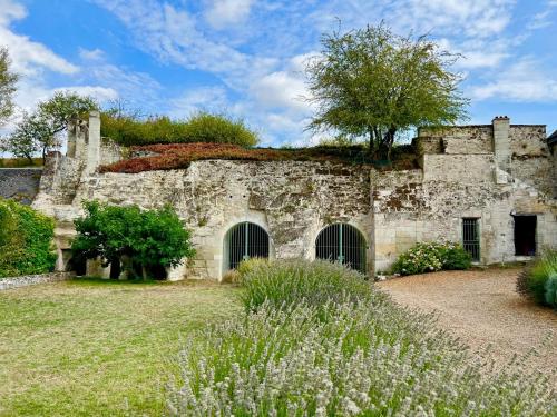 Villa de charme tourangelle في Vallères: مبنى حجري قديم مع ساحة عشب