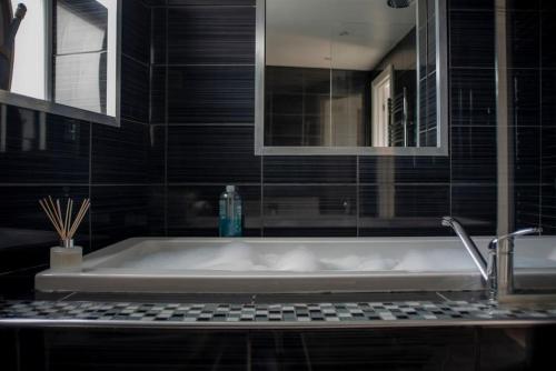 a bath tub in a bathroom with black tiles at Jewel Pier *2 Bed House* Deal in Deal