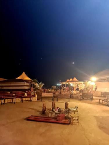 a group of tables and umbrellas on a beach at night at Hasan Zawaideh Camp in Wadi Rum