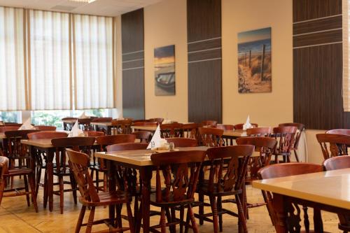 a restaurant with wooden tables and chairs and windows at Wydma Park in Rowy