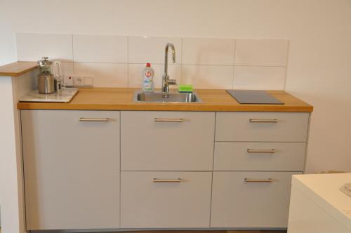een keuken met witte kasten en een wastafel bij 2-Zimmer Studio mit Terrasse und Fernblick - Marburg in Marburg an der Lahn