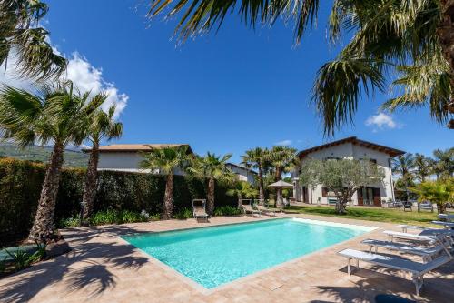 una piscina con palmeras y tumbonas en Casa Il Geranio, en Piedimonte Etneo