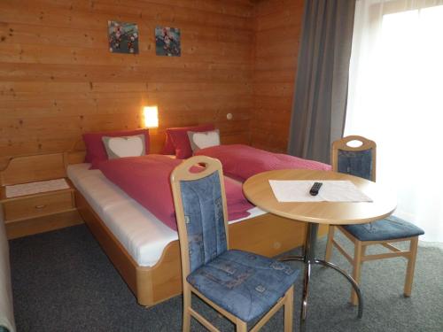 a bedroom with a bed and a small table at Pension Herzoggut in Zell am See