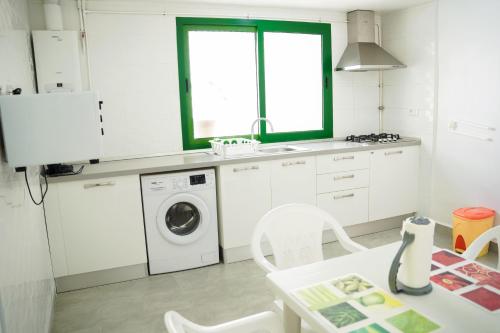 a white kitchen with a washing machine and a table at Appartement confortable proche plage et centre ville in Nabeul