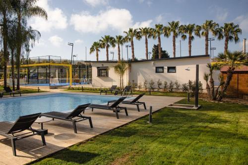 - une piscine avec des chaises et des palmiers à côté d'un bâtiment dans l'établissement B&B Villa Seta, à Agrigente