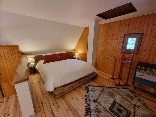 um quarto com uma cama num quarto com paredes de madeira em gîte Le Maz'eau avec jacuzzi em Saint-Pierre-de-Chartreuse
