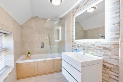 ein Badezimmer mit einer Badewanne, einem Waschbecken und einem Spiegel in der Unterkunft The Roost Group - The Coach House - HOT TUB in Gravesend
