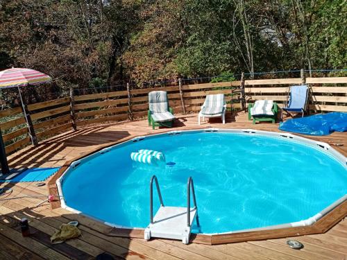 a pool on a deck with chairs and an umbrella at Maison de 4 chambres avec piscine privee jacuzzi et jardin clos a Callen in Callen