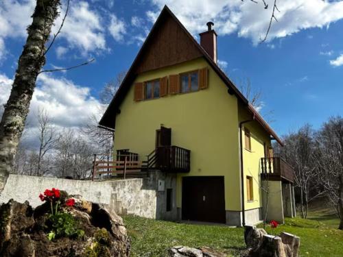 uma grande casa amarela com um telhado de gambrel em Vacation house Polane em Delnice