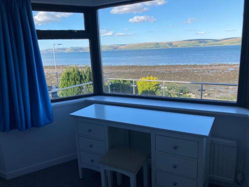 a window with a desk and a view of the ocean at Waters Edge in Stranraer