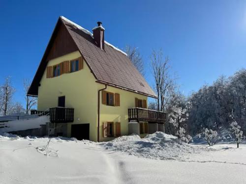 a house with snow on the ground in front of it at Vacation house Polane in Delnice