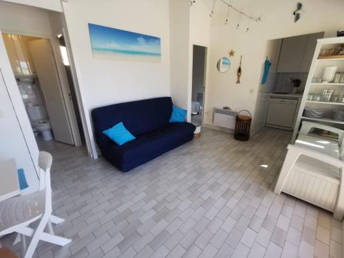 un salon avec un canapé bleu et une cuisine dans l'établissement 5026 Tennis Village 111, au Cap d'Agde