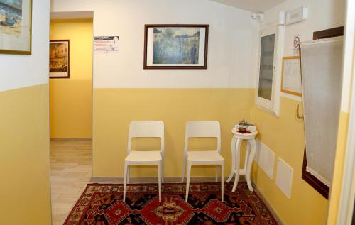 a room with two white stools and a yellow wall at Break Affittacamere in San Vito al Tagliamento