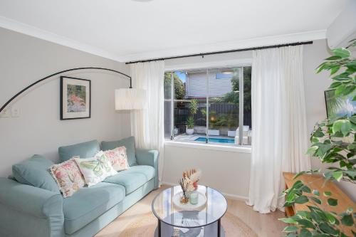 a living room with a blue couch and a window at The Forest Nest - private garden studio in Forestville