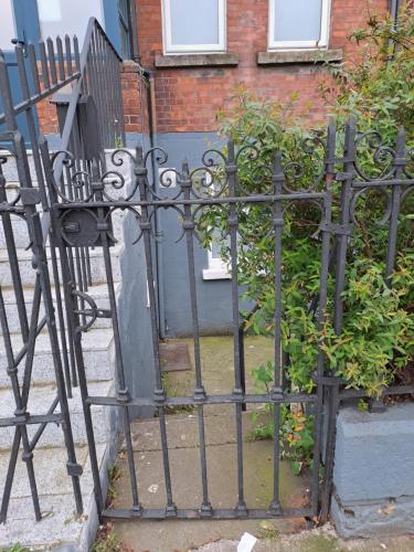 a black iron gate with a bush in front of a house at Spacious Studio-Dublin 3 in Dublin