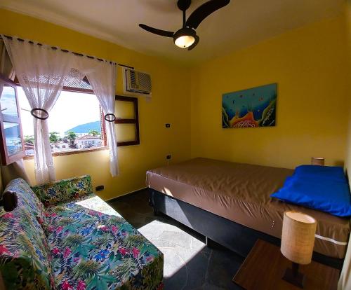 1 dormitorio con cama, sofá y ventana en Vista para Orla 3 Qts à 500m da Praia, en Ubatuba