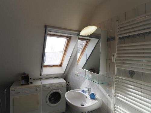 een badkamer met een wasmachine en een wastafel bij Meer, Whg 15 in Zingst