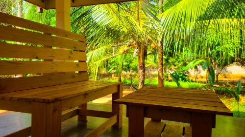 a wooden bench sitting under a porch with palm trees at Greenville Resort and Spa in Dambulla