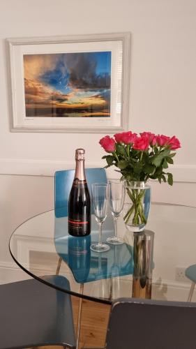 a glass table with a bottle of wine and two glasses at Little Sussex House in Rye