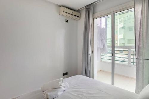 a white bedroom with a bed and a balcony at TT Holidays-Rabat City Center in Rabat