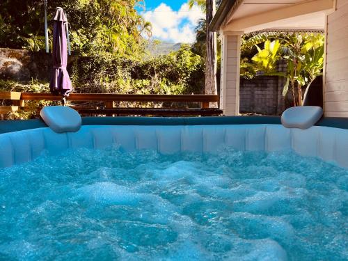 una gran piscina con sombrilla y una piscina al aire libre. en La Trinité, charme historique du Sud Sauvage en Saint-Philippe