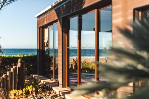 uma casa com grandes janelas com vista para a praia em Paradis Plage Surf Yoga & Spa em Taghazout