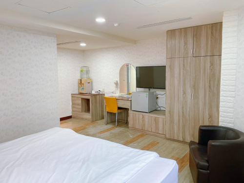 a bedroom with a bed and a desk and a television at A22 Wei Lu Hotel in Zhongli
