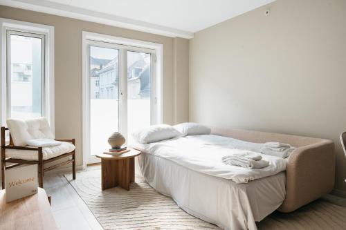 1 dormitorio blanco con 1 cama y 1 silla en Stay Urban - Stylish Scandinavian Gem with French Balcony, en Bergen