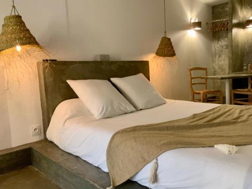um quarto com uma cama com lençóis brancos e almofadas em o5sens em Agde