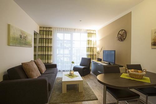 ein Wohnzimmer mit einem Sofa und einem Tisch in der Unterkunft Residenz am Balmer See - BS 12 mit Wellnessbereich in Balm