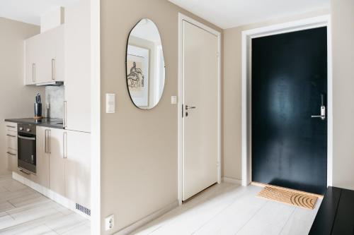 cocina blanca con puerta negra y espejo en Stay Urban - Stylish Scandinavian Gem with French Balcony, en Bergen