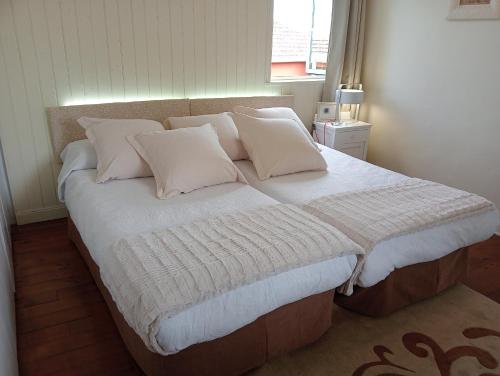 a bed with white sheets and pillows in a bedroom at CASA MARGARITAS in Ourense