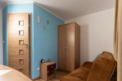a bedroom with blue walls and a brown couch at KEJB Chałupy in Chałupy