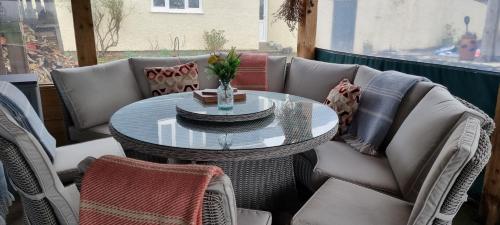 un patio con mesa de cristal y sillas en Merrifield House Devon, en Kingsbridge