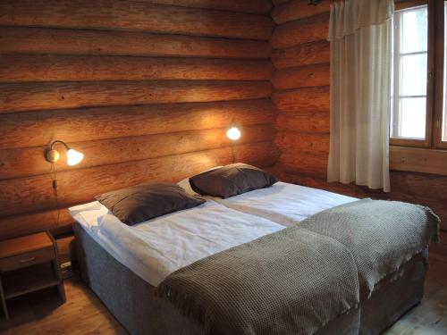 a bedroom with a bed in a wooden wall at Villa Kaidan Kunkku in Ristiina