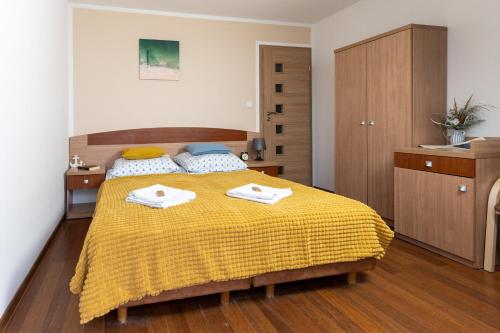 a bedroom with a yellow bed with two towels on it at KEJB Chałupy in Chałupy