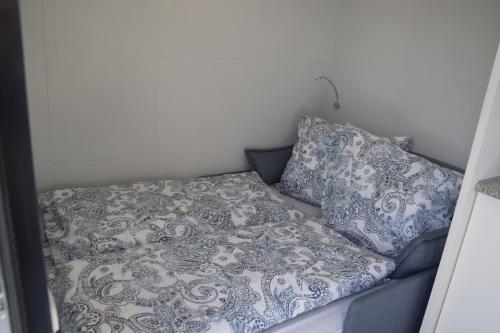 a bed with blue and white sheets and pillows at Tiny House in ruhiger Lage 