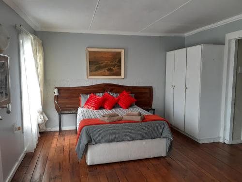 1 dormitorio con 1 cama con almohadas rojas en Granny flat, en Seafield