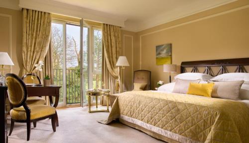 a bedroom with a bed and a desk and a window at Castlemartyr Resort Hotel in Castlemartyr