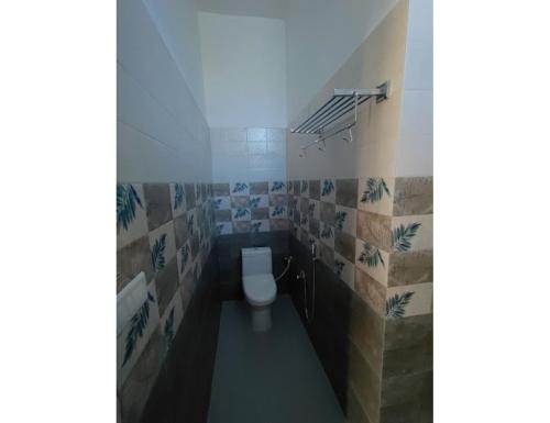 baño con aseo en una habitación con azulejos en Atulya Home Stay, Uttarkashi, en Dharāsu