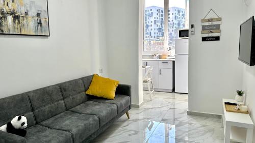 ein Wohnzimmer mit einem grauen Sofa und einem gelben Kissen in der Unterkunft Cozy one bedroom Limeapartment in Haifa