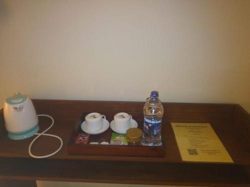 uma mesa de madeira com uma garrafa de água e uma vela em MercuryFM 103 Guest House - Colombo 3 em Colombo